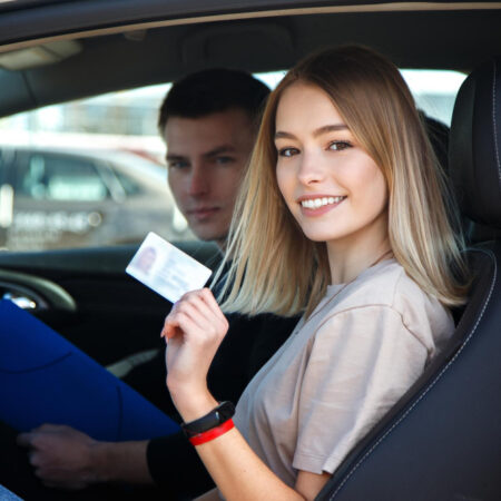 chica alegre conduciendo coche entrenamiento tarjeta licencia conducir sus manos